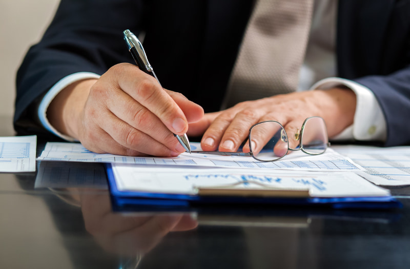 Person using pen and paper to learn how to write an effective public sector report conclusion