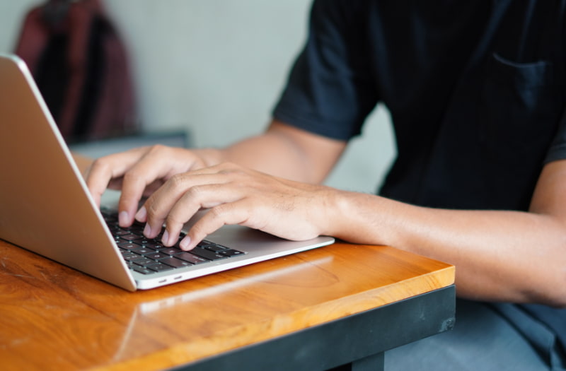 person using a laptop to learn how to write an effective public sector report introduction