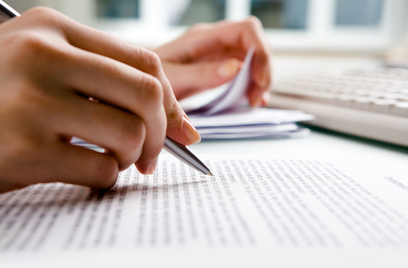 Person using a pen to evaluate a tender request and choose the right tender