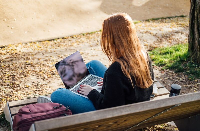 Person sat on a bench using a laptop to learn about uses for AI in learning and development