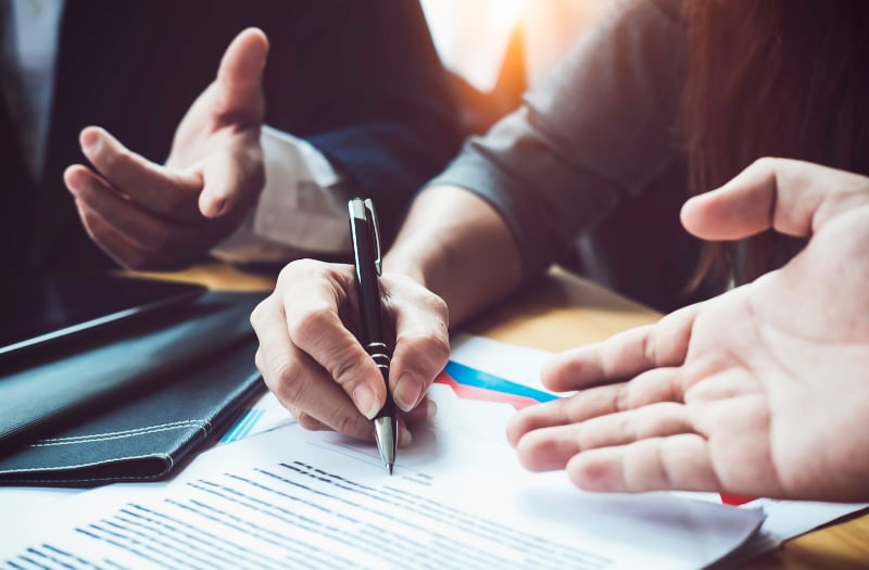 Person using pen and paper to write down contract risk management types